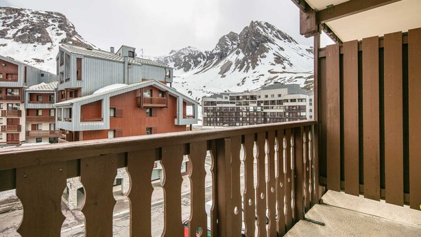 Varanda com vista para montanhas cobertas de neve e edifícios modernos.