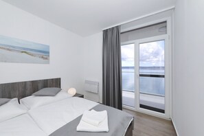 Ein modernes Hotelzimmer mit Bett, Nachttisch, einem Fenster mit Vorhängen und einem Gemälde an der Wand.