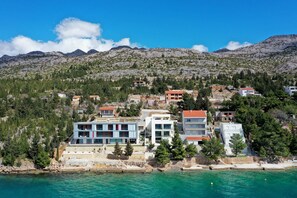 Eine Küstenstadt mit moderner Architektur, blauem Meer und Bergen im Hintergrund.