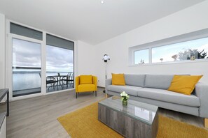 Ein modernes Wohnzimmer mit grauem Sofa, gelbem Sessel und einem Glastisch.