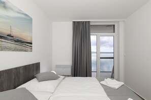 Ein modernes Hotelzimmer mit Bett, Meerblick und großem Fenster.