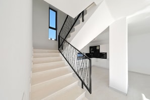 A modern staircase with a geometric railing, leading to a kitchen area with white cabinetry and a window. - Villa Astur with Private Pool (Zemunik Gornji)