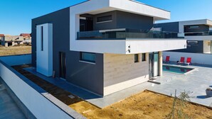 A modern two-story house with a balcony, a swimming pool, and a view of neighboring houses. - Villa Astur with Private Pool (Zemunik Gornji)
