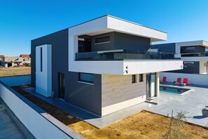 A modern two-story house with a balcony, a swimming pool, and a view of neighboring houses. - Villa Astur with Private Pool (Zemunik Gornji)