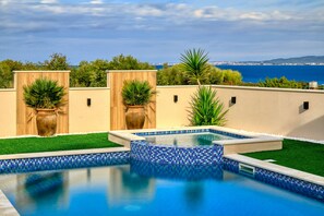 A swimming pool with a blue mosaic border, surrounded by green artificial grass and potted plants. - Villa Masanda with Pool (Dobropoljana)
