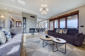 A modern living room with a fireplace, a sofa, two coffee tables, and a dining area with chairs. - Villa Masanda with Pool (Dobropoljana)