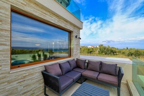 A modern outdoor seating area with a glass wall, a sectional sofa, and a metal table. - Villa Masanda with Pool (Dobropoljana)