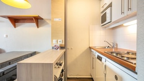 A compact kitchen with a wooden countertop, white cabinets, a microwave, and a dishwasher. - Charming studio for 4 people, with a balcony and a view of the ski slope (Tignes)