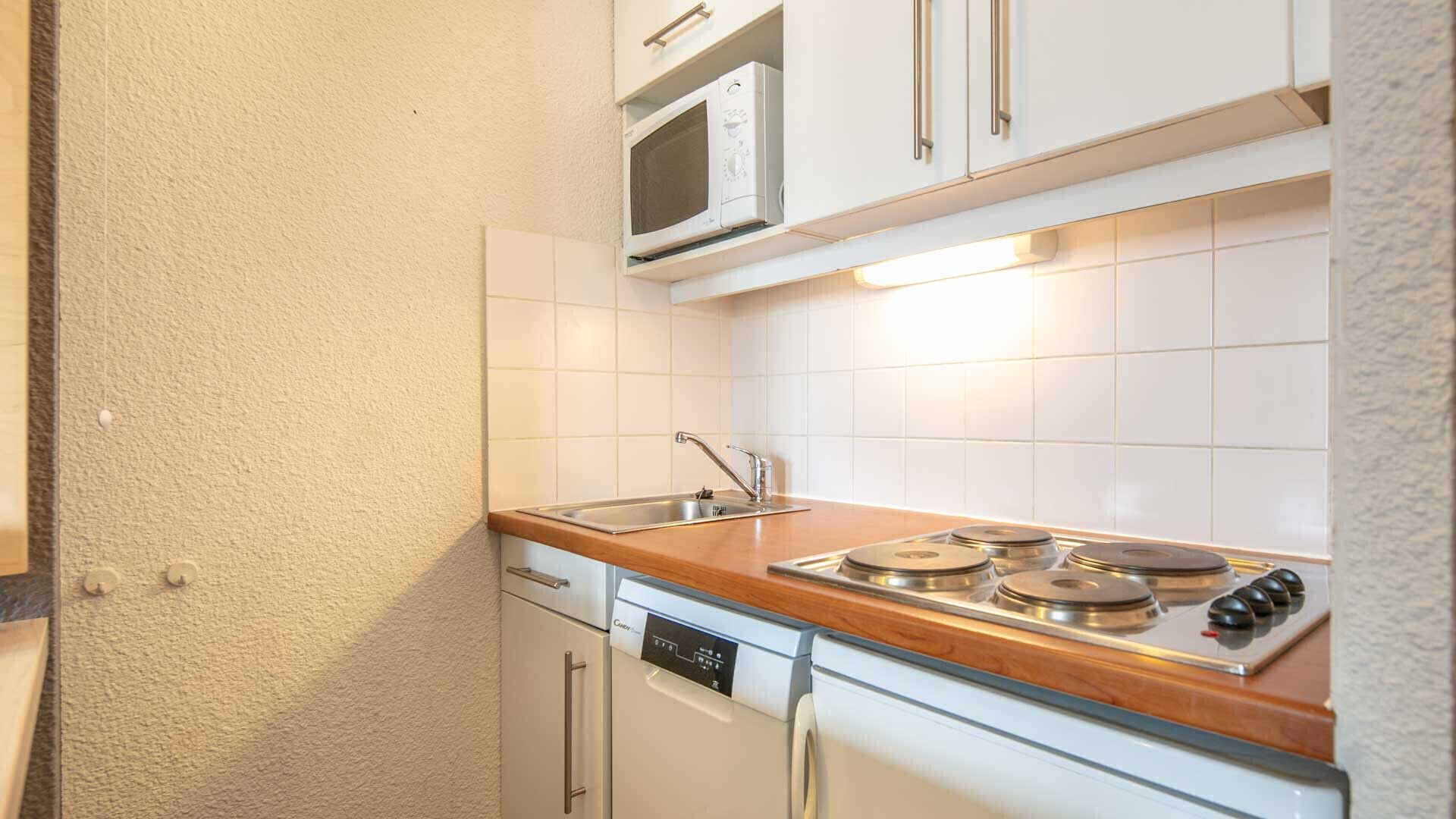 Cocina compacta equipada con microondas, fregadero, lavavajillas y estufa.