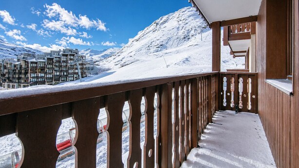 A snow-covered balcony with a wooden railing overlooking a mountainous landscape and a row of buildings. - Charming studio for 4 people, with a balcony and a view of the ski slope (Tignes)