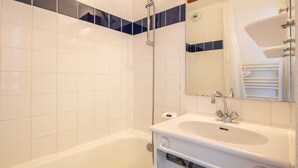 A bathroom with a bathtub, a sink, a mirror, and a shower. - Small, fully furnished studio for 4 people, with a balcony overlooking the ski slope (Tignes)