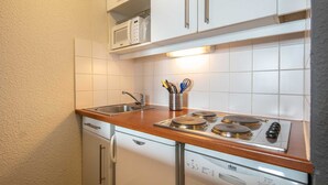 A compact kitchen with a sink, stove, and microwave. - Small, fully furnished studio for 4 people, with a balcony overlooking the ski slope (Tignes)
