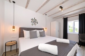 Ein Schlafzimmer mit Bett, Nachttisch, Wandbild und einem Fenster mit Vorhängen.