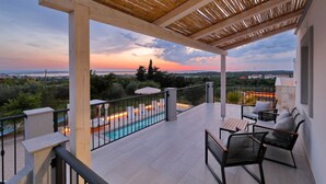 Un espacio al aire libre cubierto con piscina, mobiliario y vistas al paisaje.