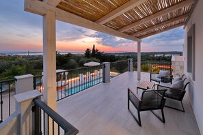 Ein überdachter Außenbereich mit Pool, Sitzgelegenheiten und Blick auf die Landschaft.