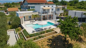 Una casa de varios pisos con piscina, mobiliario exterior y jardín.