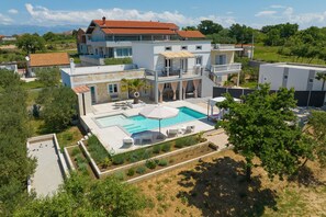 Ein mehrstöckiges Haus mit Swimmingpool, Sitzgelegenheiten im Freien und einem Garten.