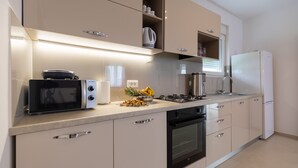 Una cocina moderna con microondas, horno y refrigerador, además de frutero en la encimera.
