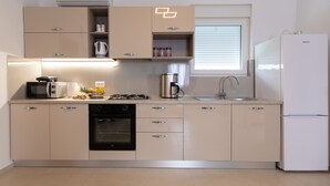Una cocina moderna con electrodomésticos integrados, una ventana con persianas y un refrigerador.