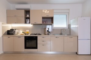 Eine moderne Küche mit eingebauten Geräten, einem Fenster mit Jalousien und einem Kühlschrank.