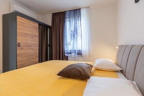 Ein Schlafzimmer mit Bett, Kissen, Kleiderschrank und einem fenster mit Vorhängen.