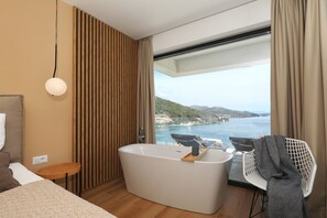 A modern bathroom with a freestanding bathtub, a small round table, and a chair. - Apartment Mentis with Sea View (Marina)