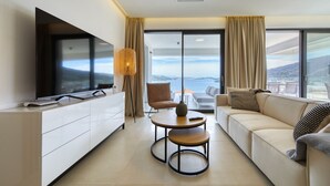 A modern living room with a flat-screen TV, a sofa, a coffee table, and a view of the sea. - Apartment Mentis with Sea View (Marina)