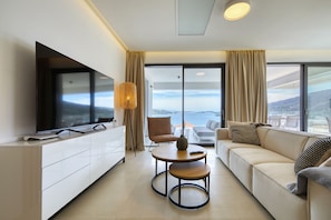 A modern living room with a flat-screen TV, a sofa, a coffee table, and a view of the sea. - Apartment Mentis with Sea View (Marina)
