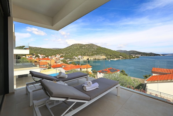 A balcony with two sun loungers and a view of a coastal town. - Apartment Mentis with Sea View (Marina)