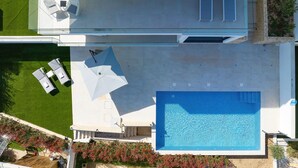An aerial view of a modern house with a swimming pool, a patio with lounge chairs, and a garden. - Apartment Mentis with Sea View (Marina)