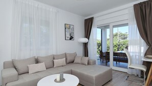 Ein modernes Wohnzimmer mit einem Ecksofa, einem runden Couchtisch und einem Essbereich mit Stuhl und Tisch.