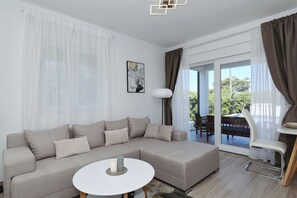 Ein modernes Wohnzimmer mit einem Ecksofa, einem runden Couchtisch und einem Essbereich mit Stuhl und Tisch.