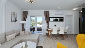 Ein modernes Wohnzimmer mit einer Couch, einem Esstisch, Stühlen und einem leuchtend gelben Sessel.