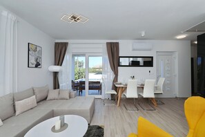 Ein modernes Wohnzimmer mit einer Couch, einem Esstisch, Stühlen und einem leuchtend gelben Sessel.
