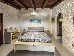 Quarto com cama, escrivaninha, cadeira, quadro e escada.