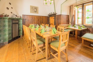 Un espace repas avec des tables et des chaises en bois, un mur recouvert de carreaux verts et un buffet en bois.