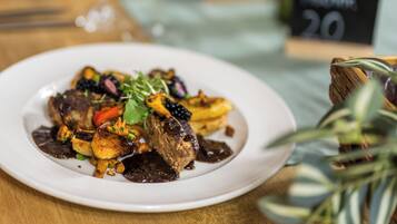 Ein Teller mit Speisen, darunter verschiedene Gemüsesorten und ein Fleischgericht, vermutlich ein Steak, auf einem weißen Teller.