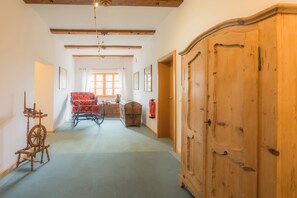 Une pièce spacieuse avec une armoire en bois, un rouet et une fenêtre avec des rideaux.