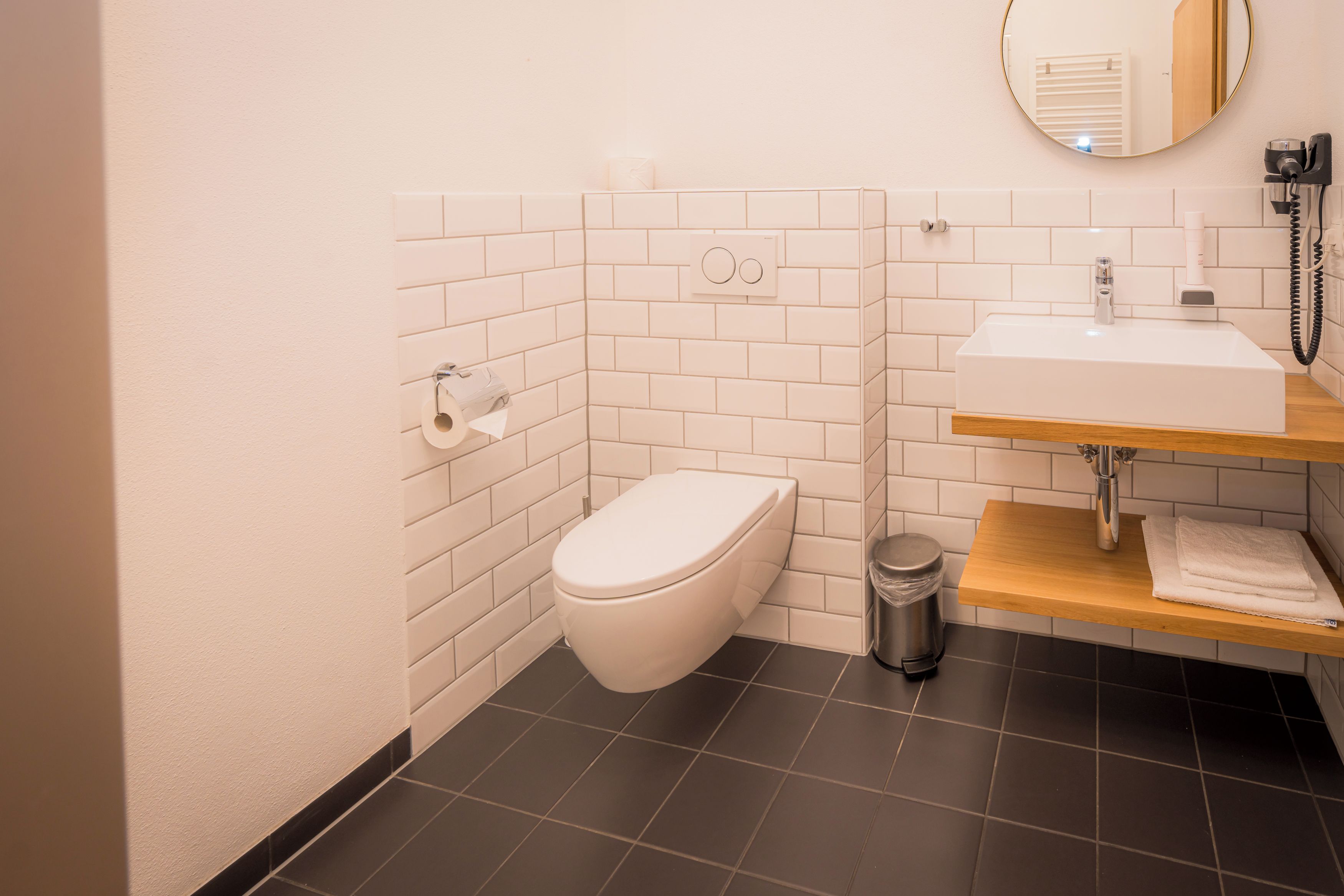 Ein modernes Badezimmer mit Toilette, Waschbecken und Spiegel.