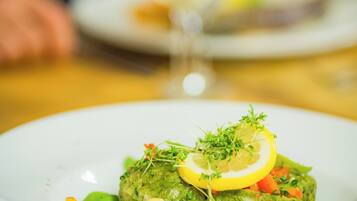 A plate of food with a green sauce, lemon, and vegetables.