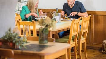 Un comedor con mobiliario de madera, una mesa con platos y cubiertos, y un jarrón con flores.