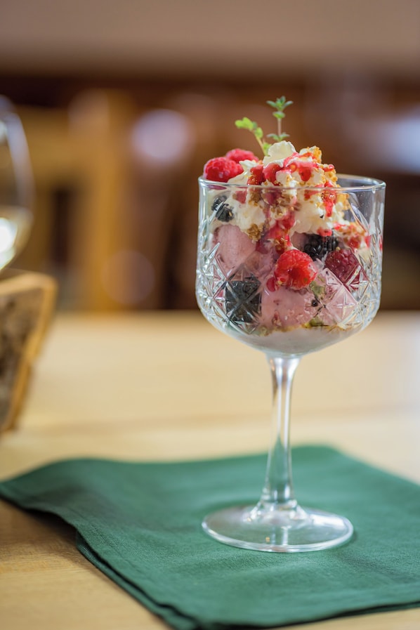 A dessert in a glass bowl on a table with a green napkin underneath.