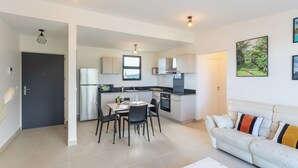 A modern kitchen with a dining area, a sofa, and a painting on the wall. - Atea Pearl (Pirae)