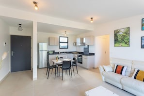 A modern apartment with a kitchen, dining area, and living room. - Atea Pearl (Pirae)