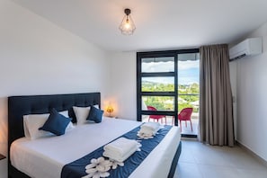 A hotel room with a bed, a window with curtains, a red chair, and an air conditioning unit. - Atea Pearl (Pirae)