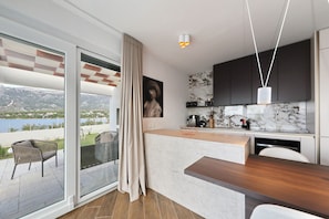 A modern kitchen with a marble backsplash, a wooden countertop, and a view of a balcony with a chair.