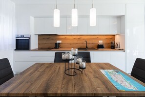 A modern kitchen with white cabinets, a wooden countertop, and pendant lights. - Villa Mariva with Heated Pool (Vir)