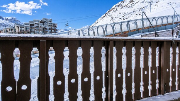 Una muntanya plena de neu amb un telefèric i edificis al fons.