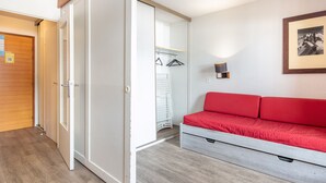 Una habitació amb un llit, un armari, un penjallabecs i una fotografia emmarcada a la paret.