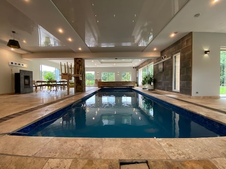A swimming pool with a stone border, a wooden bench, and a stone fireplace.. Villa "Lafamosia" with Indoor Pool and Jacuzzi